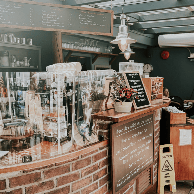 Interior of a cozy café with a counter, menu boards, and shelves of items.