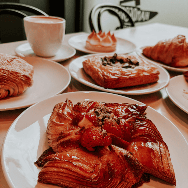 Plates of pastries and desserts arranged on a café table.