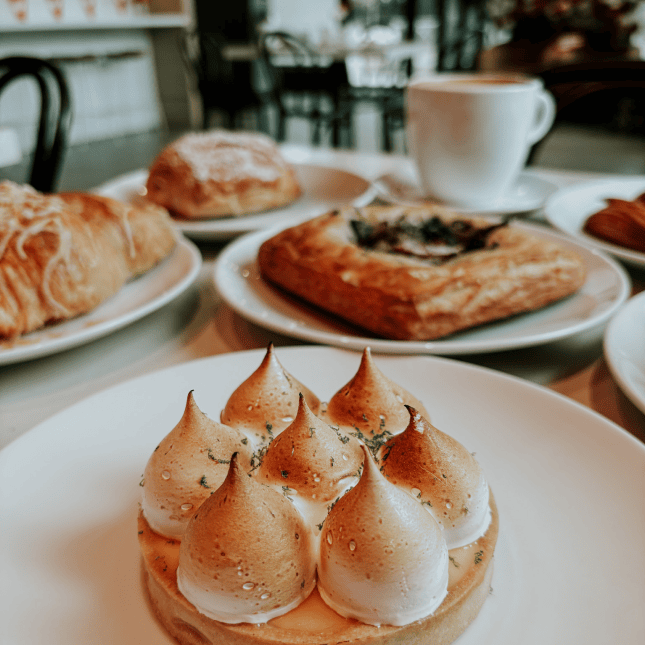 A table set with pastries and small baked desserts on white plates.