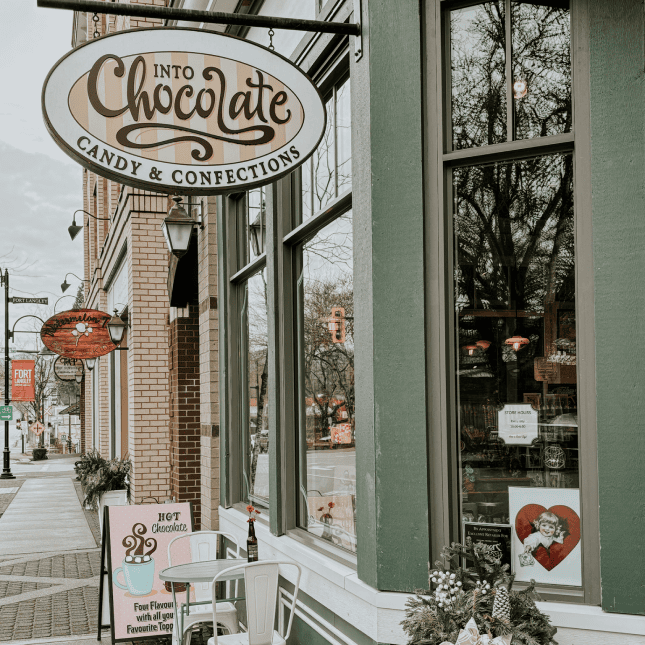 Exterior view of a boutique storefront with a hanging shop sign.