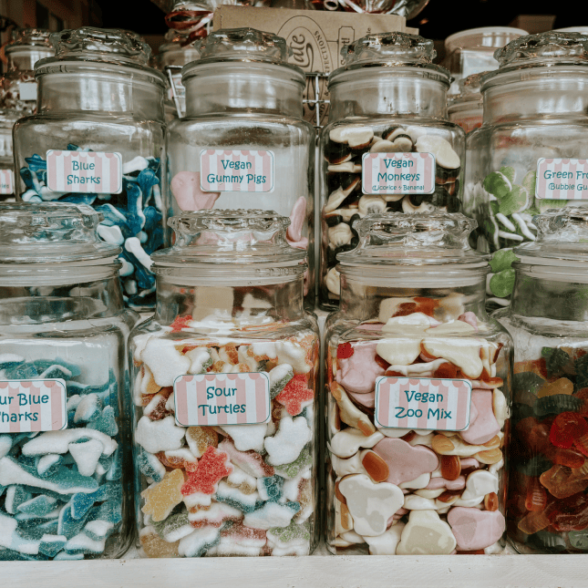 Glass jars filled with assorted candy displayed on store shelves.