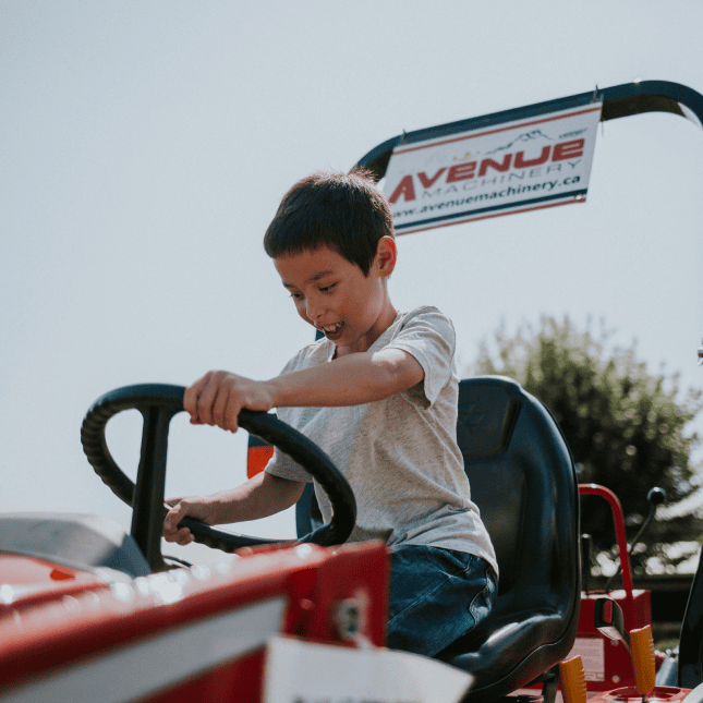 Child riding a pedal tractor at a farm attraction.