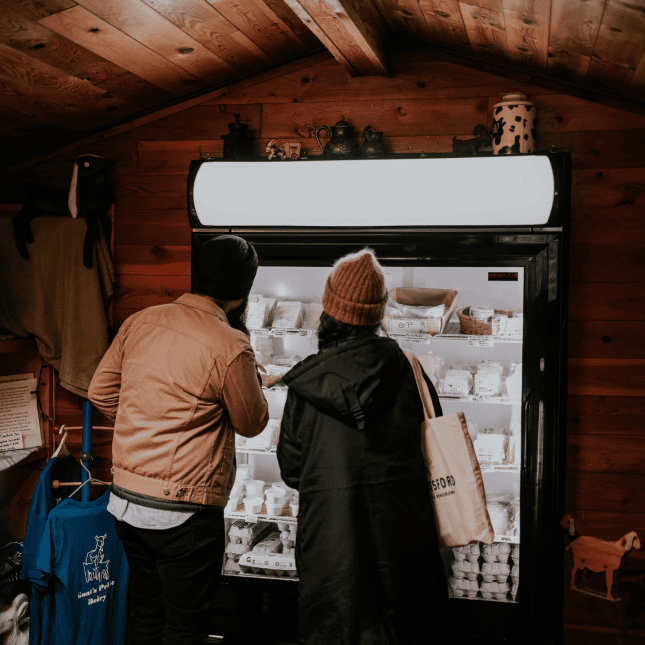 Two people ordering at a small wooden farm stand.