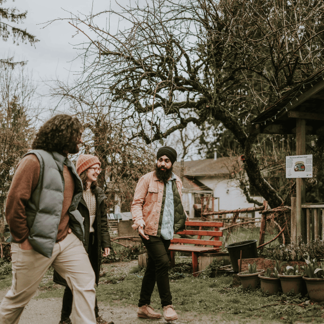 People walking through an outdoor farm area with trees.