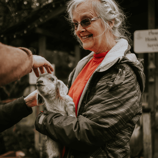 Woman smiling while holding a baby goat.