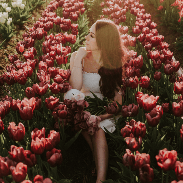 Woman sitting among deep pink tulips.