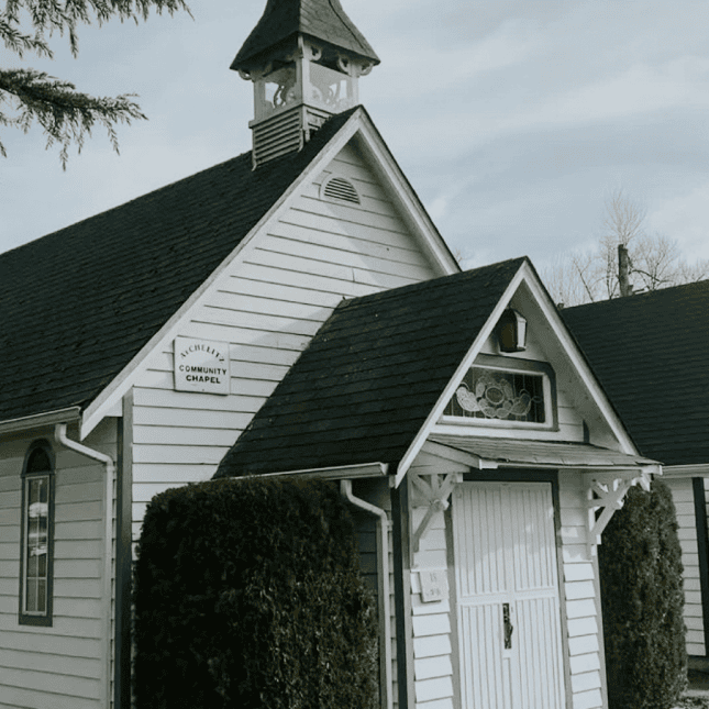 Exterior of a small historic white building.
