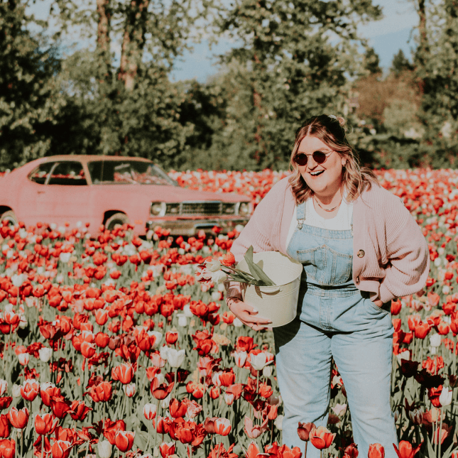 Woman smiling while walking through a tulip field.