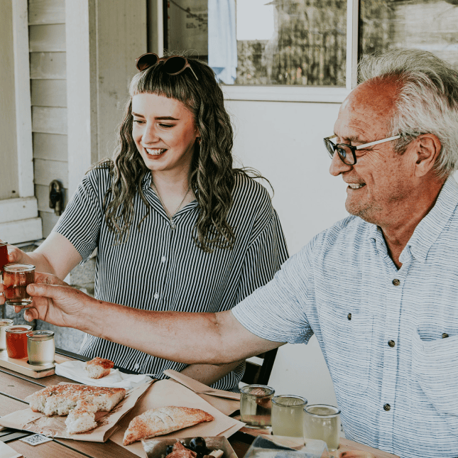 Two people enjoying drinks at a cider tasting table.