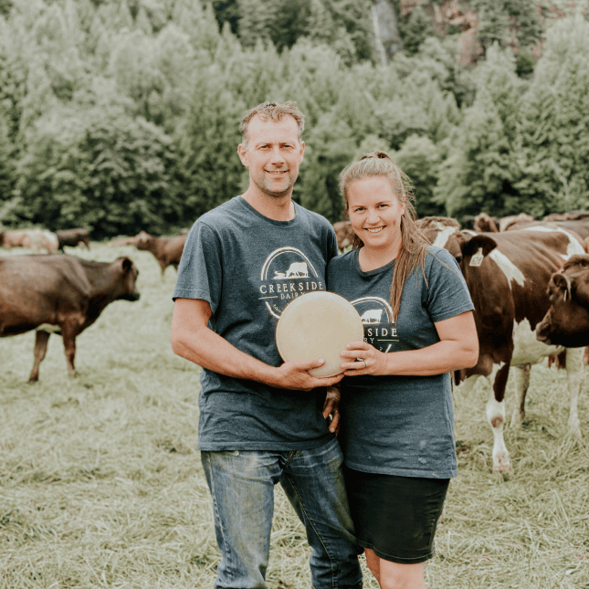 Two farmers standing in a field with water buffalo.