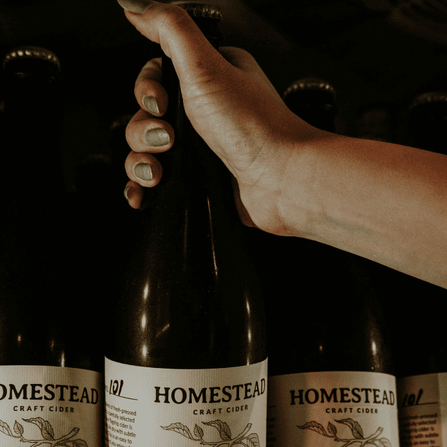 Person holding a bottle inside a tasting room.