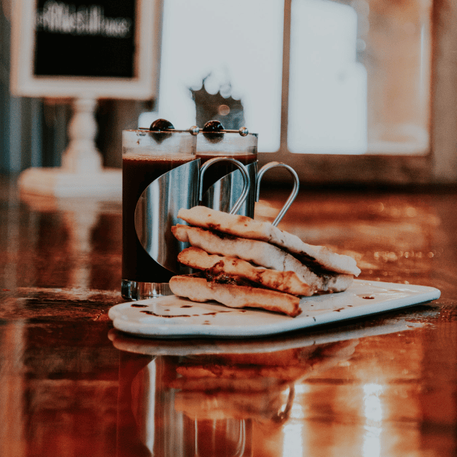 Close-up of plated food and a cocktail on a polished bar top.